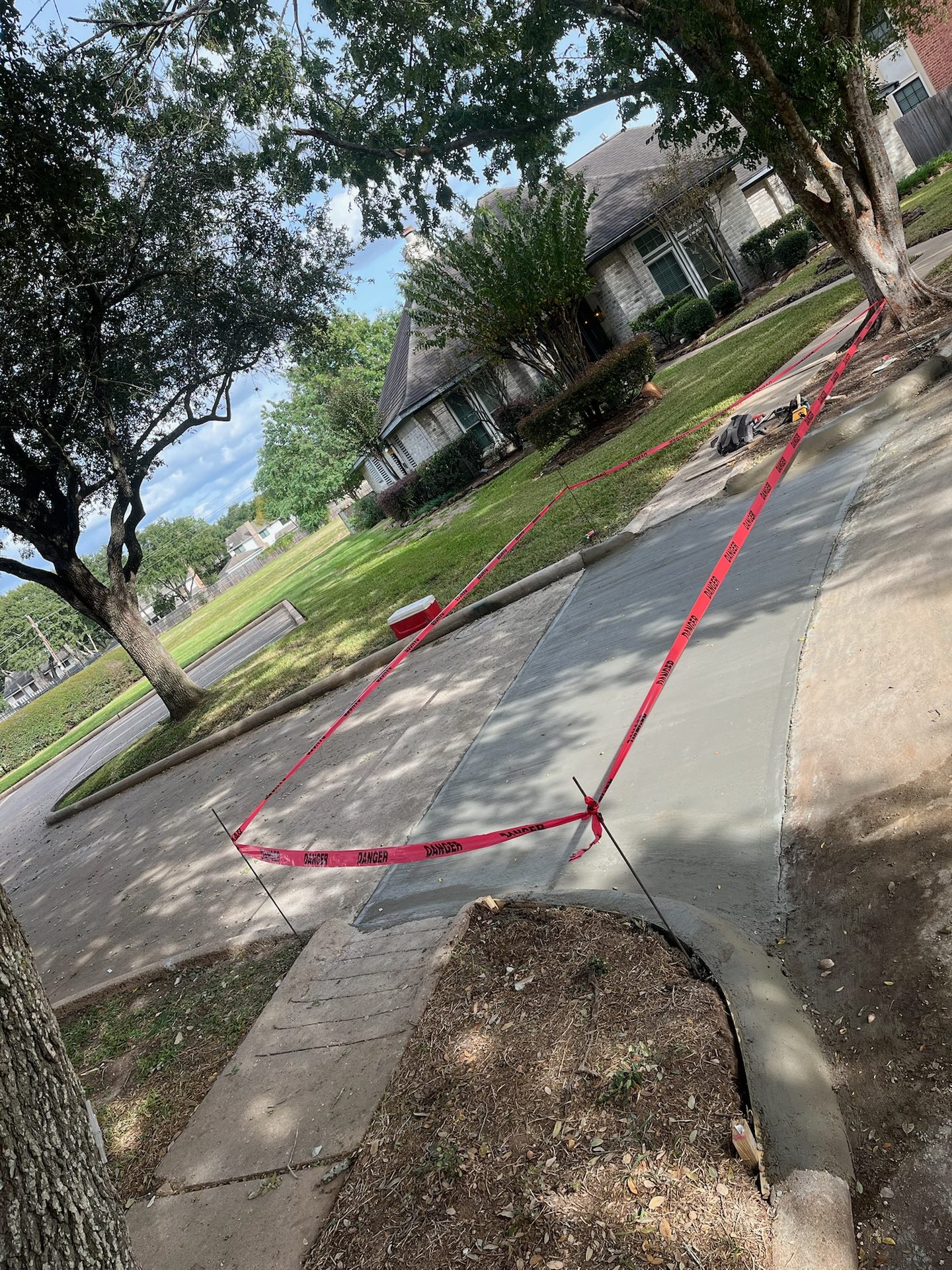 Sidewalk pour curing behind caution tape on a residential job site